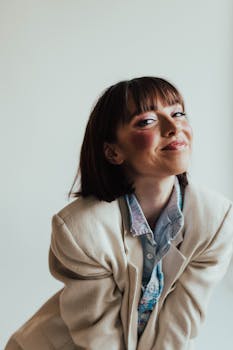 A confident woman with short hair smiles warmly in a beige blazer.