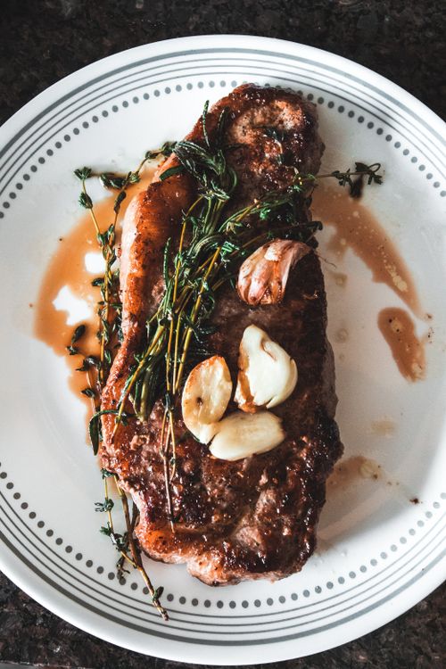 Free Succulent grilled steak with garlic and herbs on a white plate. Stock Photo