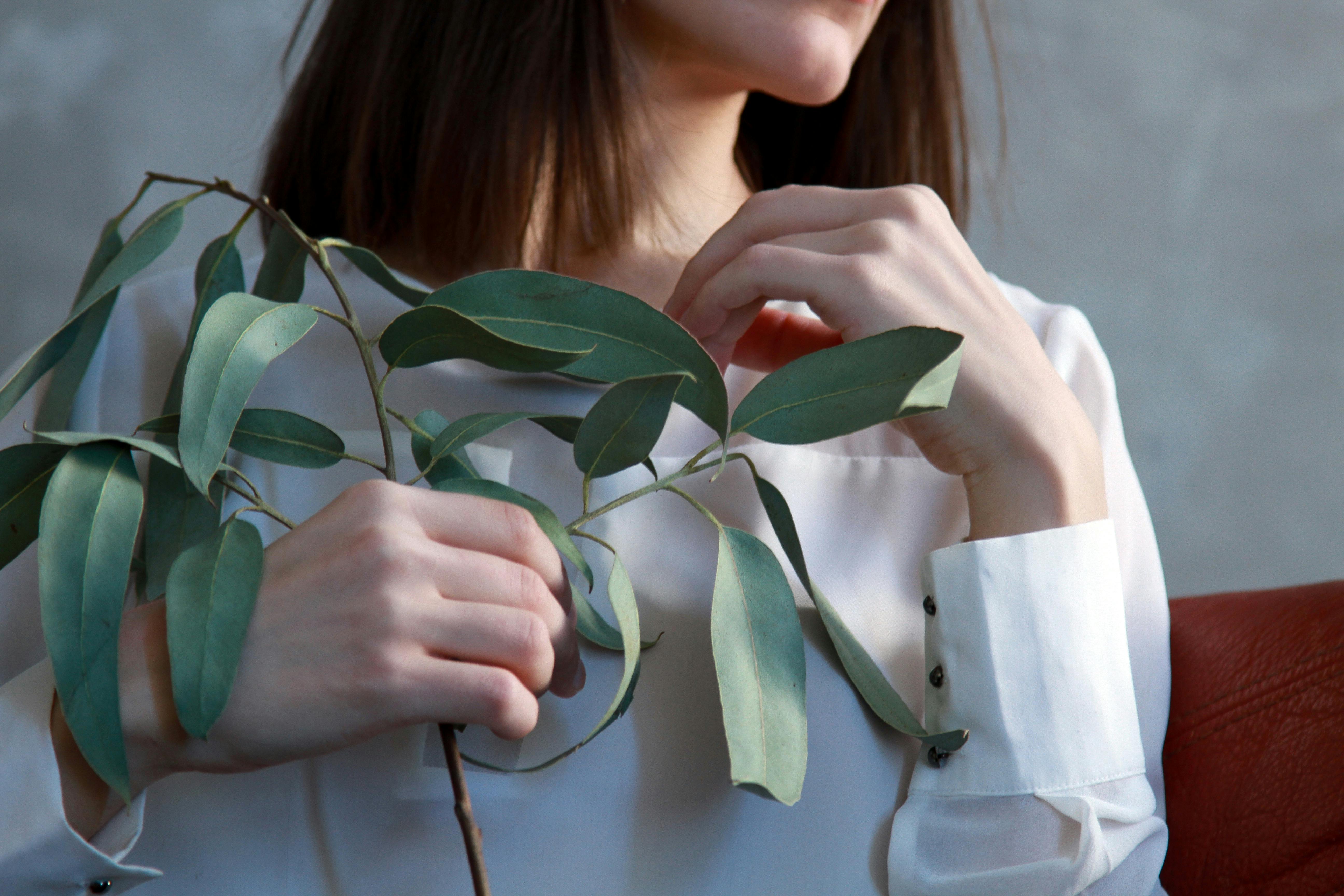 优雅的特写镜头中，一位手持桉树叶的女子在户外环境中展现了自然之美