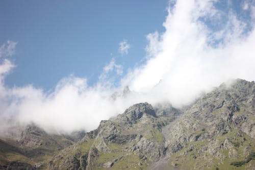Rock Mountains in Fog against Blue Sky 