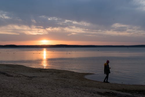A Person Standing on Sea Side During Golden Hour