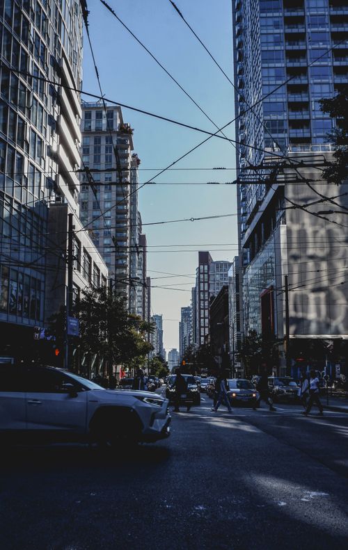 Free Vibrant city street with skyscrapers, traffic, and pedestrians under electric lines. Stock Photo