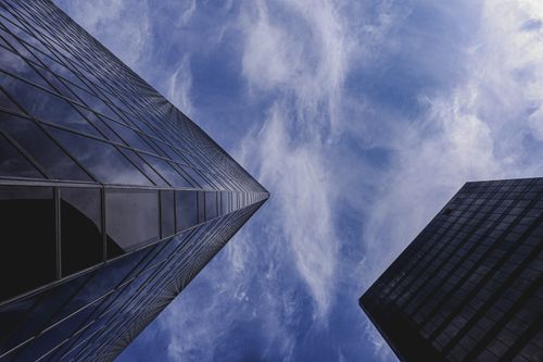 Free Stunning low angle shot of towering glass skyscrapers against a vibrant blue sky with fluffy clouds. Stock Photo