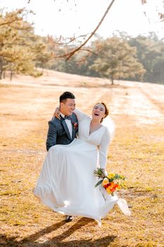 Bride and groom laughing together in a sunny outdoor setting, full of love and happiness.
