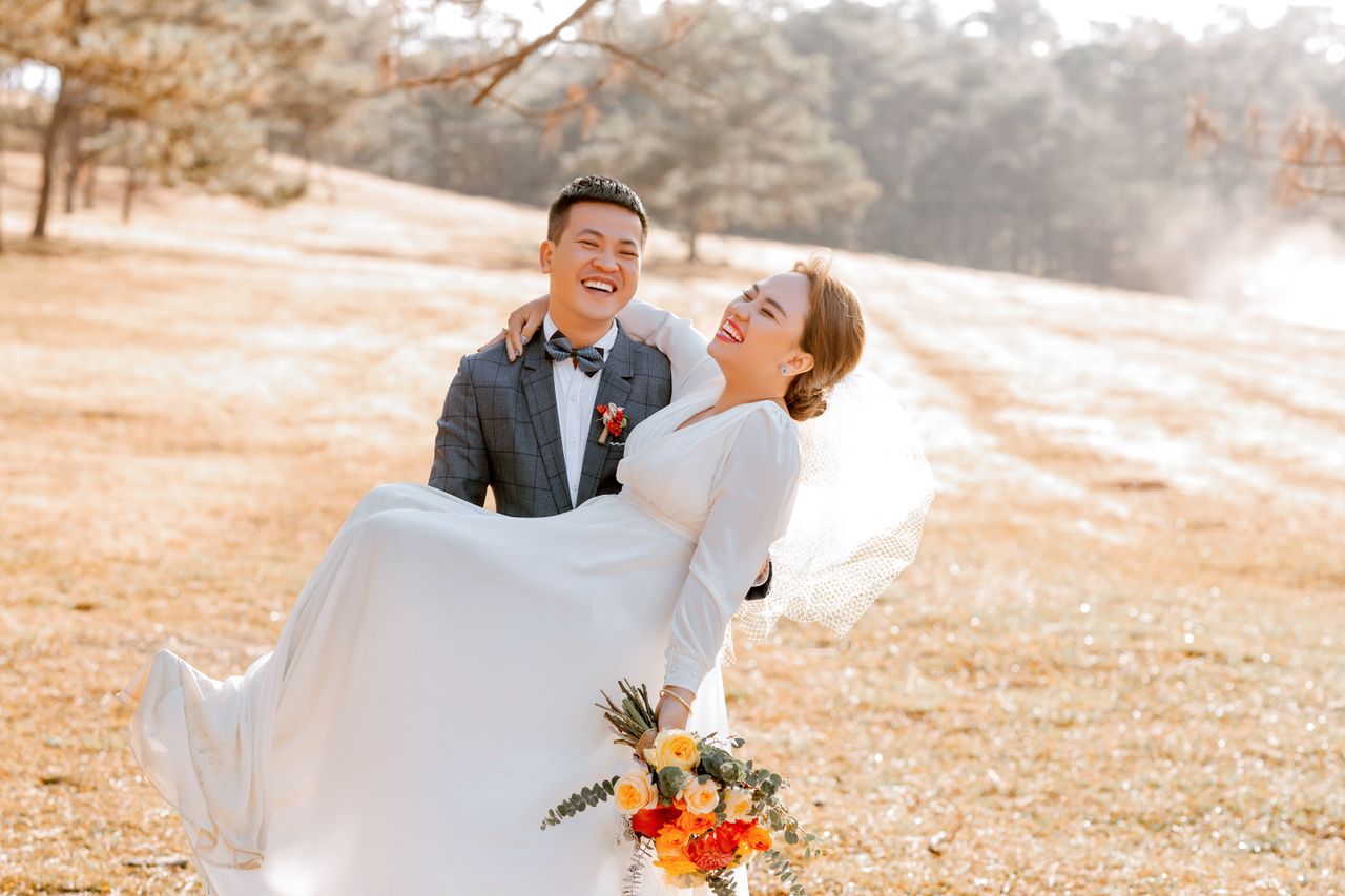 happy couple in wedding attire celebrating outdoors in a sunny meadow