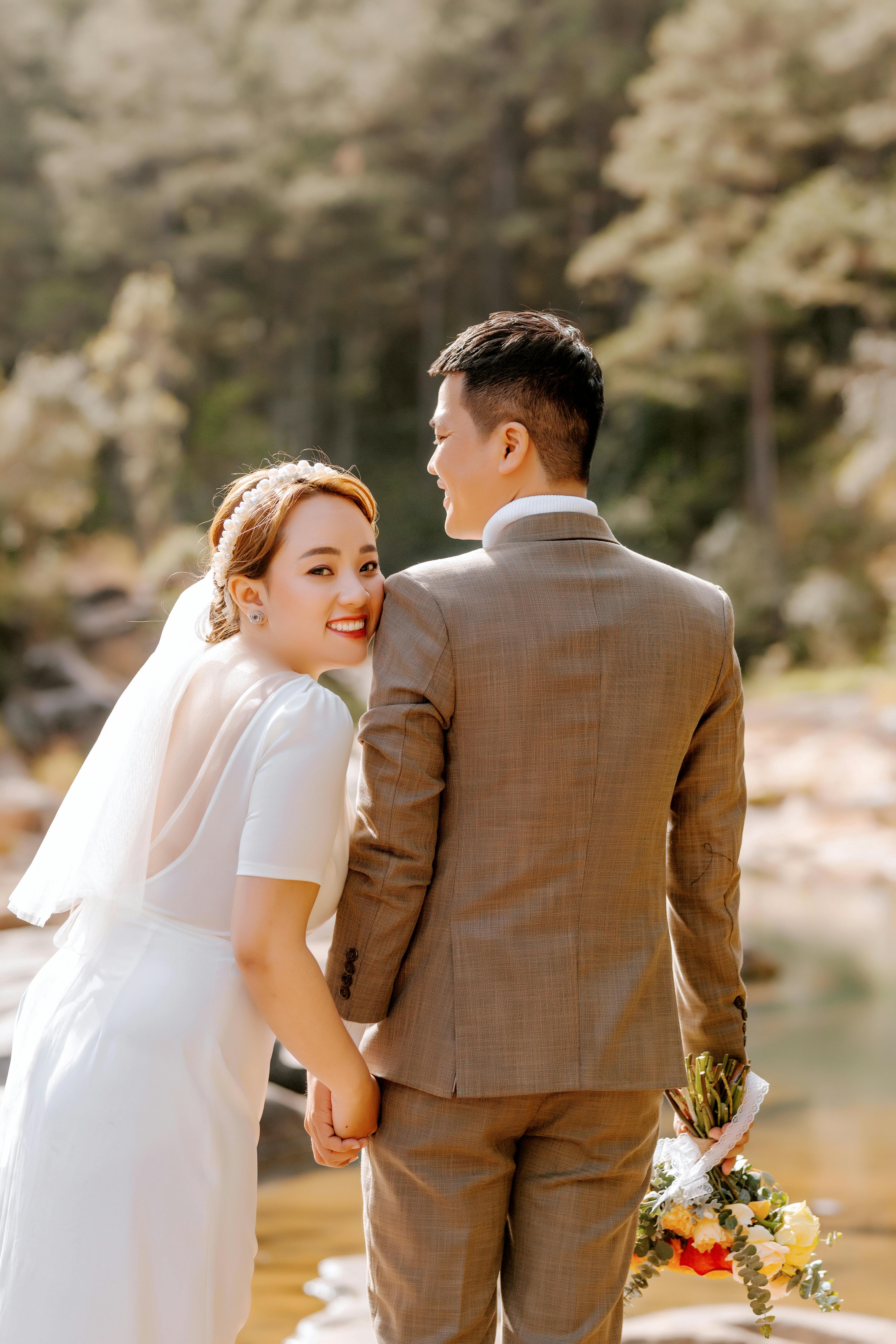 man in brown suit jacket kissing woman in white dress