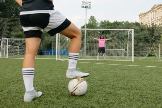 Soccer player in action aiming for the goal with a goalkeeper ready to defend.