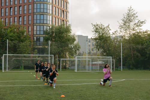 Free A group of kids performing warm-up exercises with their coach on a soccer field. Stock Photo