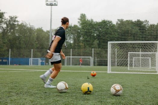 A woman practicing soccer on an outdoor field with multiple soccer balls and goals.