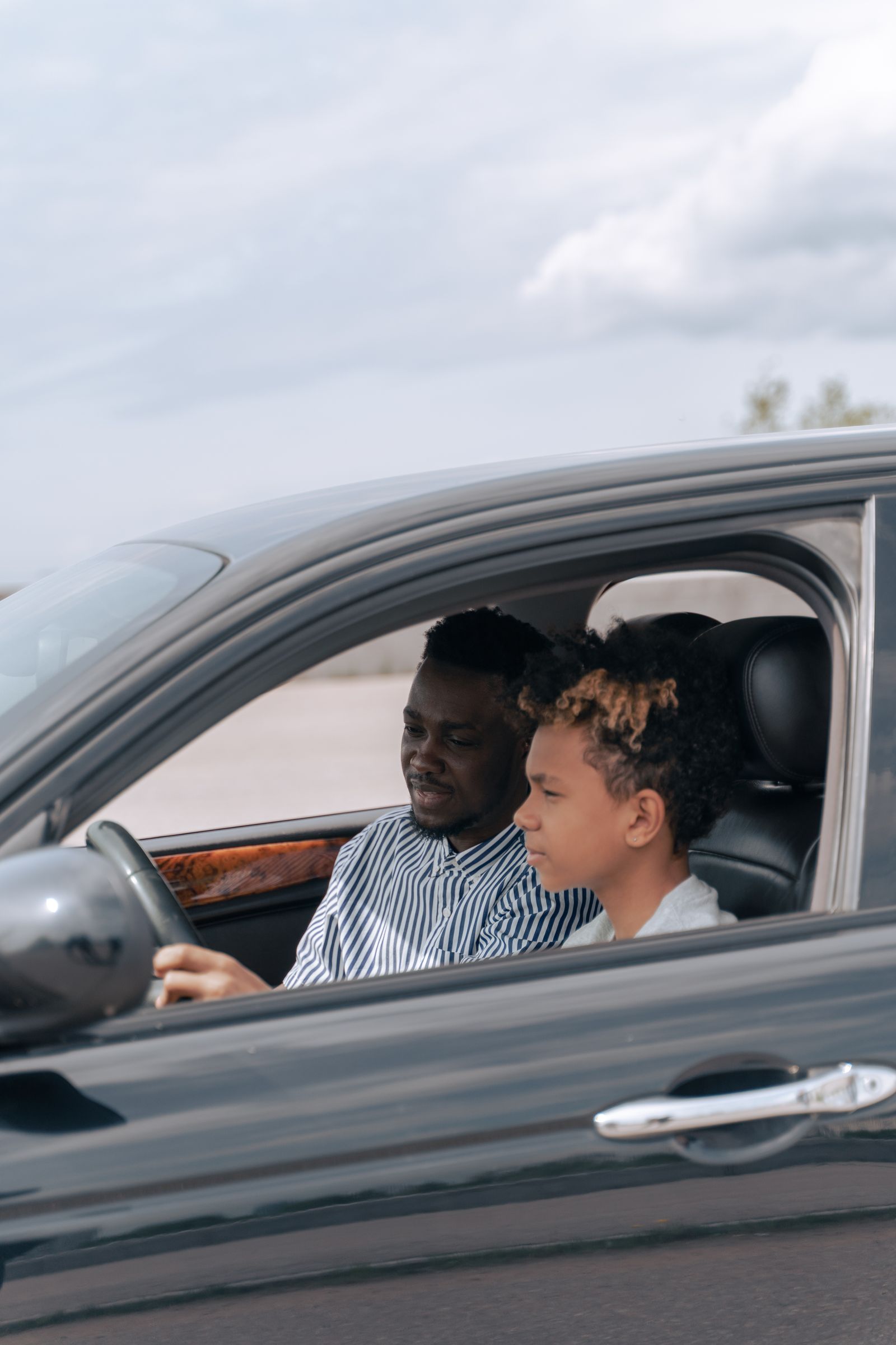 An instructor guiding a new driver during an in-car lesson on a bright day