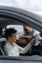 Adult Man Looking at a Teenager Seated on Driver's Side of a Car