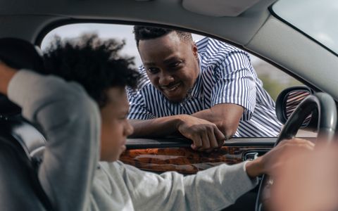 A parent teaching a teen how to drive from the passenger seat