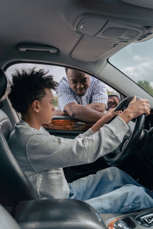 Man in Gray Long Sleeve Shirt and Blue Denim Jeans Sitting on Drivers Seat