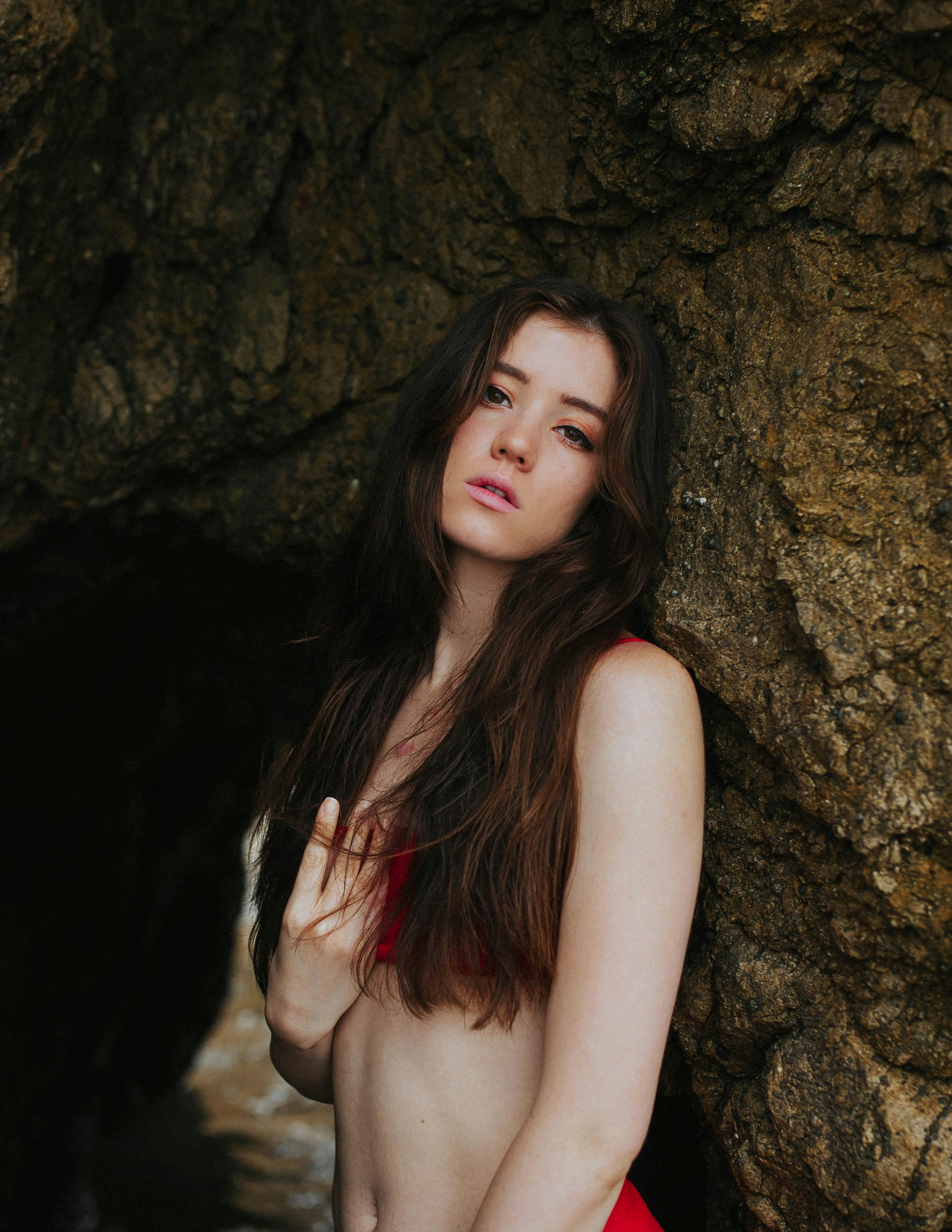 Gratis Wanita Dengan Tank Top Hitam Bersandar Di Batu Coklat Foto Stok