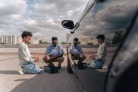 Father and son kneeling together outdoors, learning car maintenance with tools.