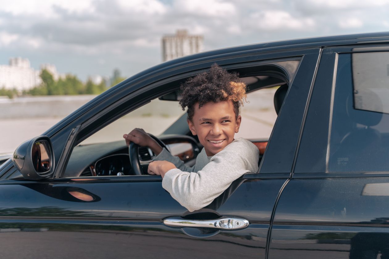 Jovem sorridente sentado ao volante de um carro