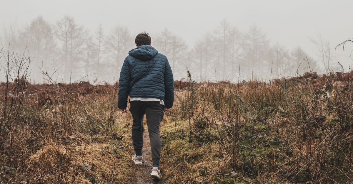person walking on a foggy path in the woods, symbolic of faith and trust