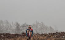 雾蒙蒙的森林里，一名女子独自站着，戴着彩色围巾