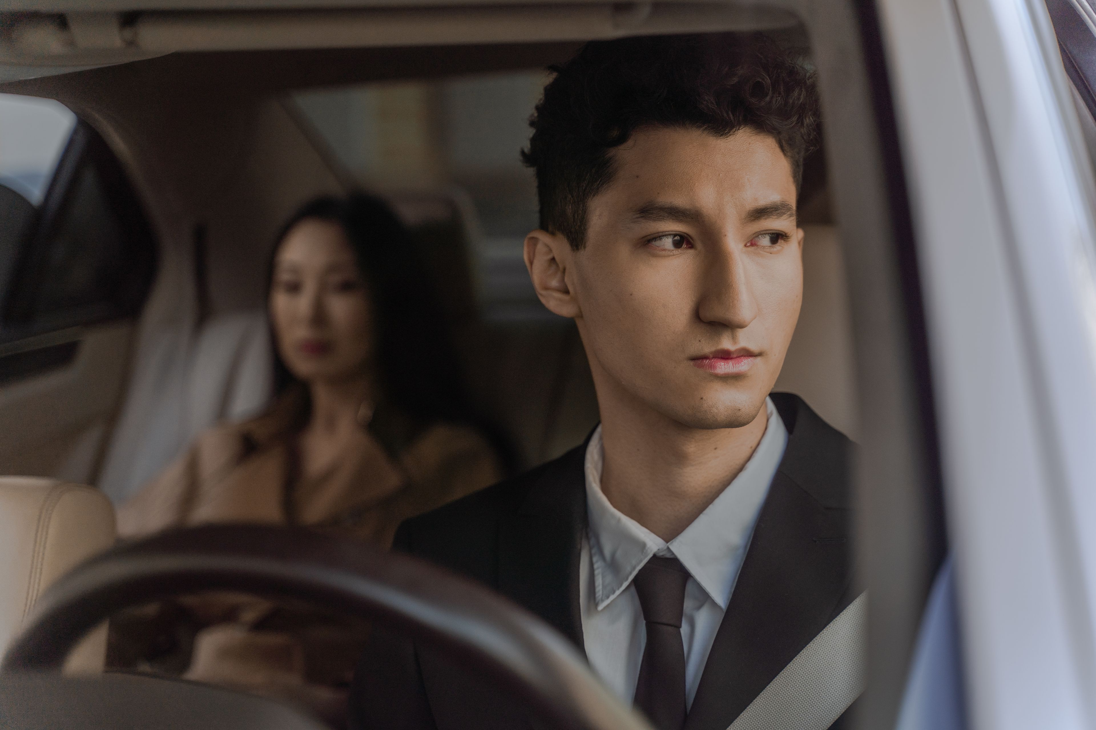 A professional chauffeur waiting beside a luxury car