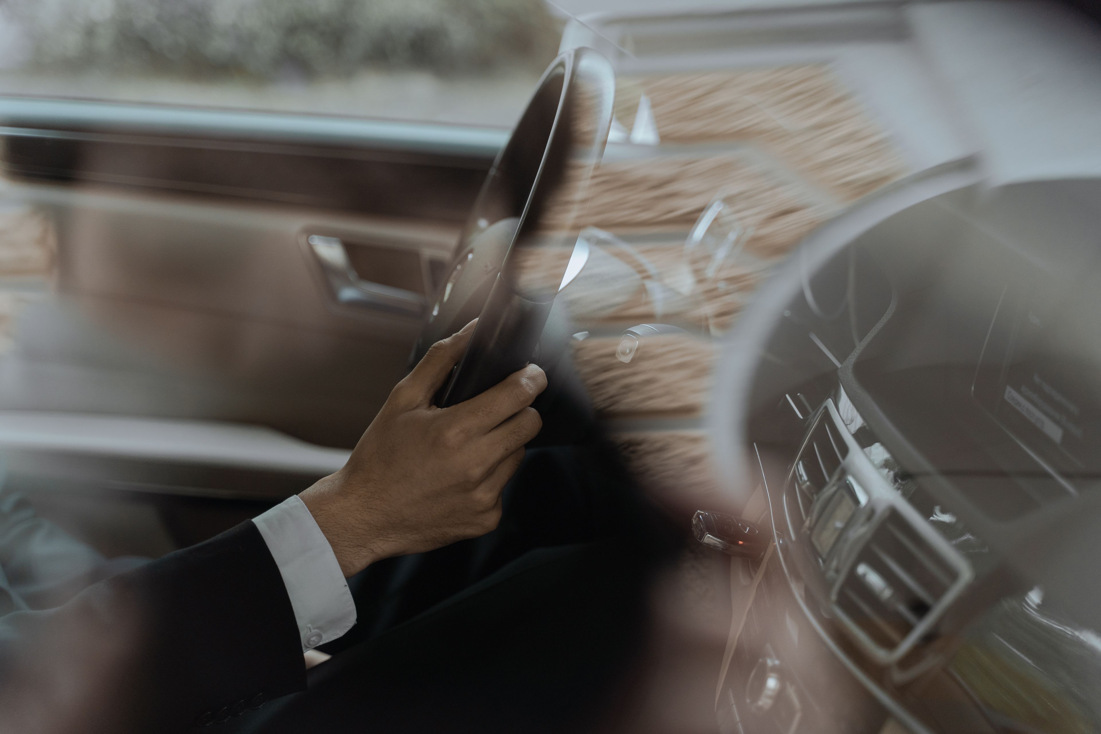 A professional chauffeur waiting beside a luxury car