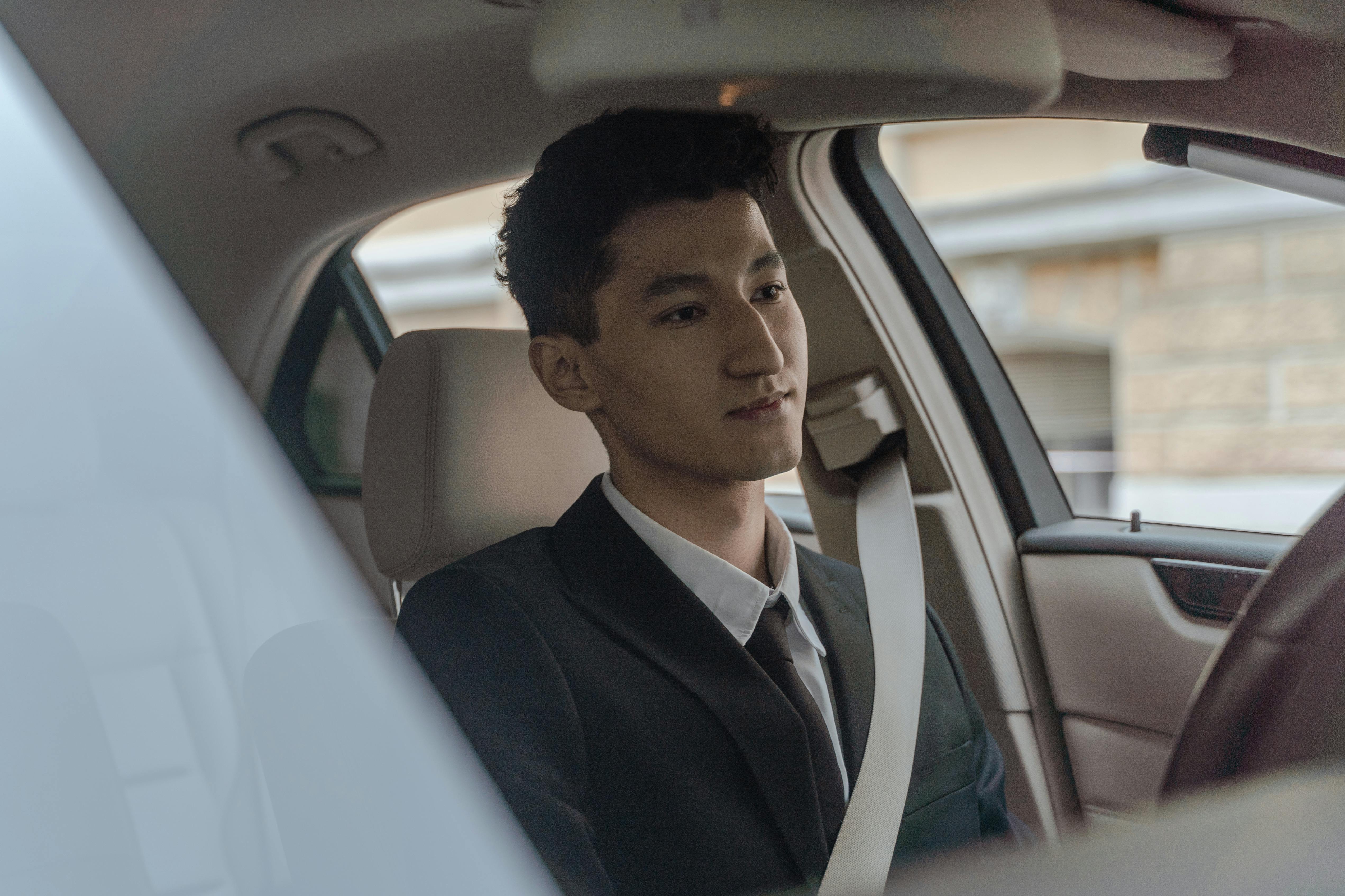 man in black suit sitting on car seat