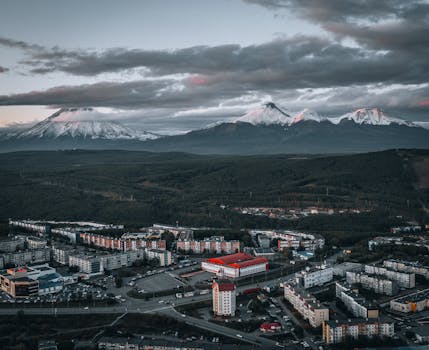 Stunning aerial view of a cityscape at dusk with snow-capped volcanoes in the background.