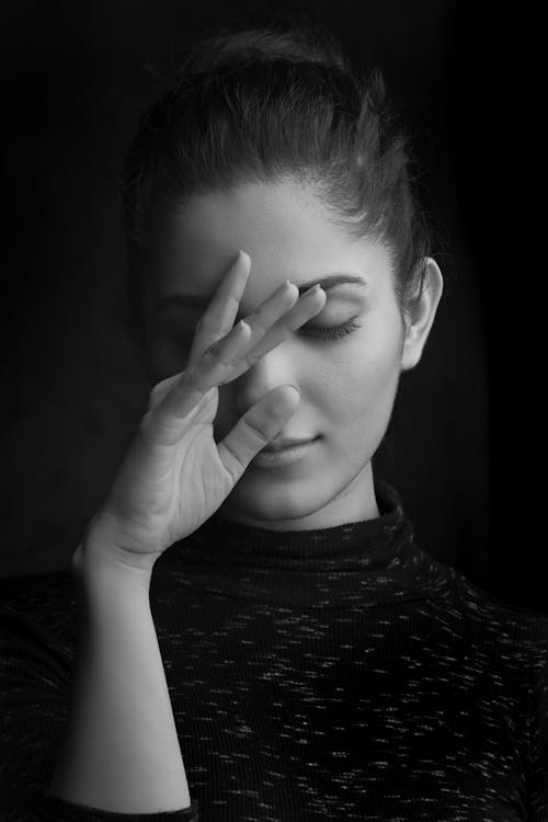 A Grayscale Photo of a Woman Covering Her Face