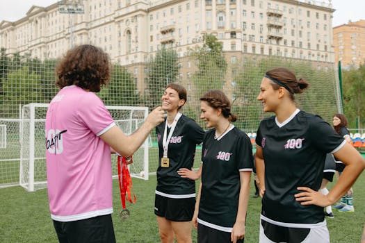 Women's football team receiving medals after a successful game outdoors, showcasing teamwork and celebration.