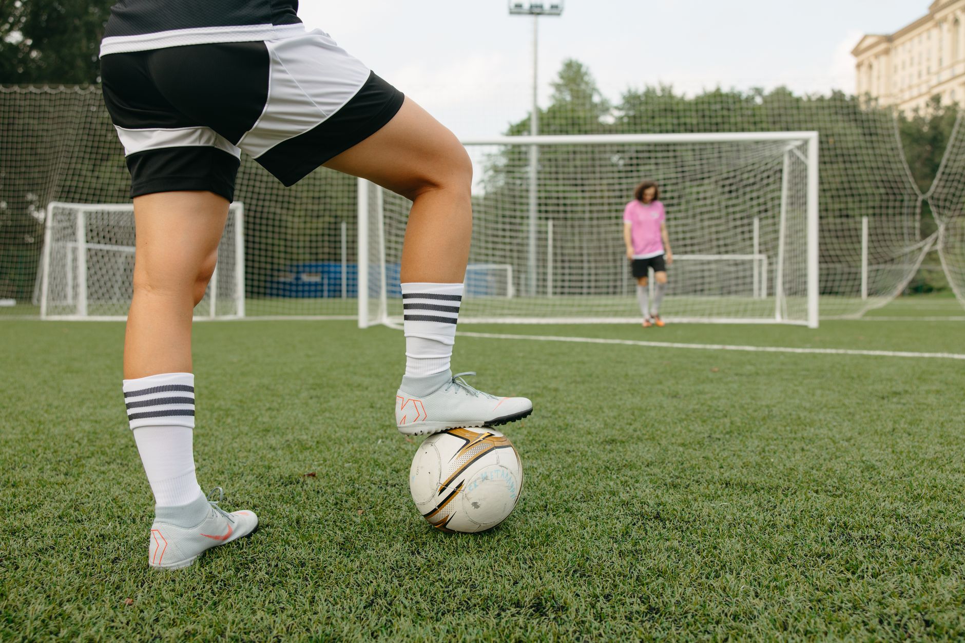 Beginner footballers practicing short passes beside cones on a sunny community field