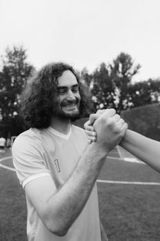 Black and white image of a smiling soccer player shaking hands on the field.