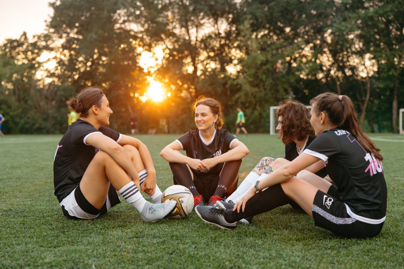 Group of women athletes sitting together on grass after a sports activity