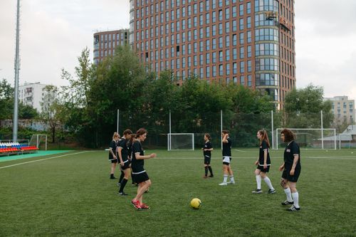 Free Energetic women's soccer team practicing on a green field with urban buildings in the background. Stock Photo