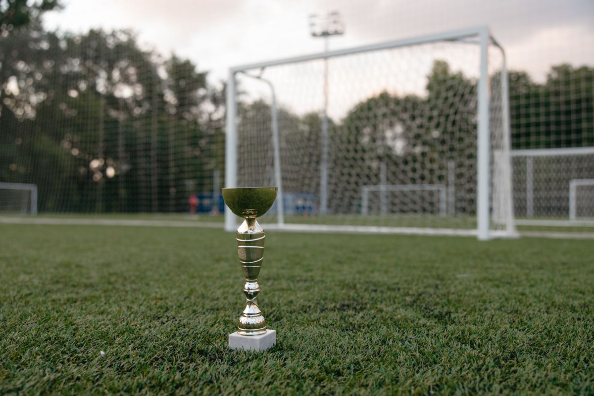 Futbol sahası yakınında kripto para simgeli altın kupa