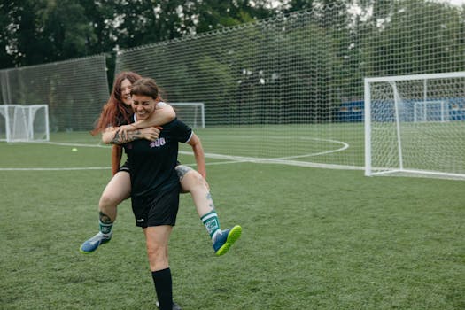 Two women having fun on a soccer field, expressing joy and camaraderie.