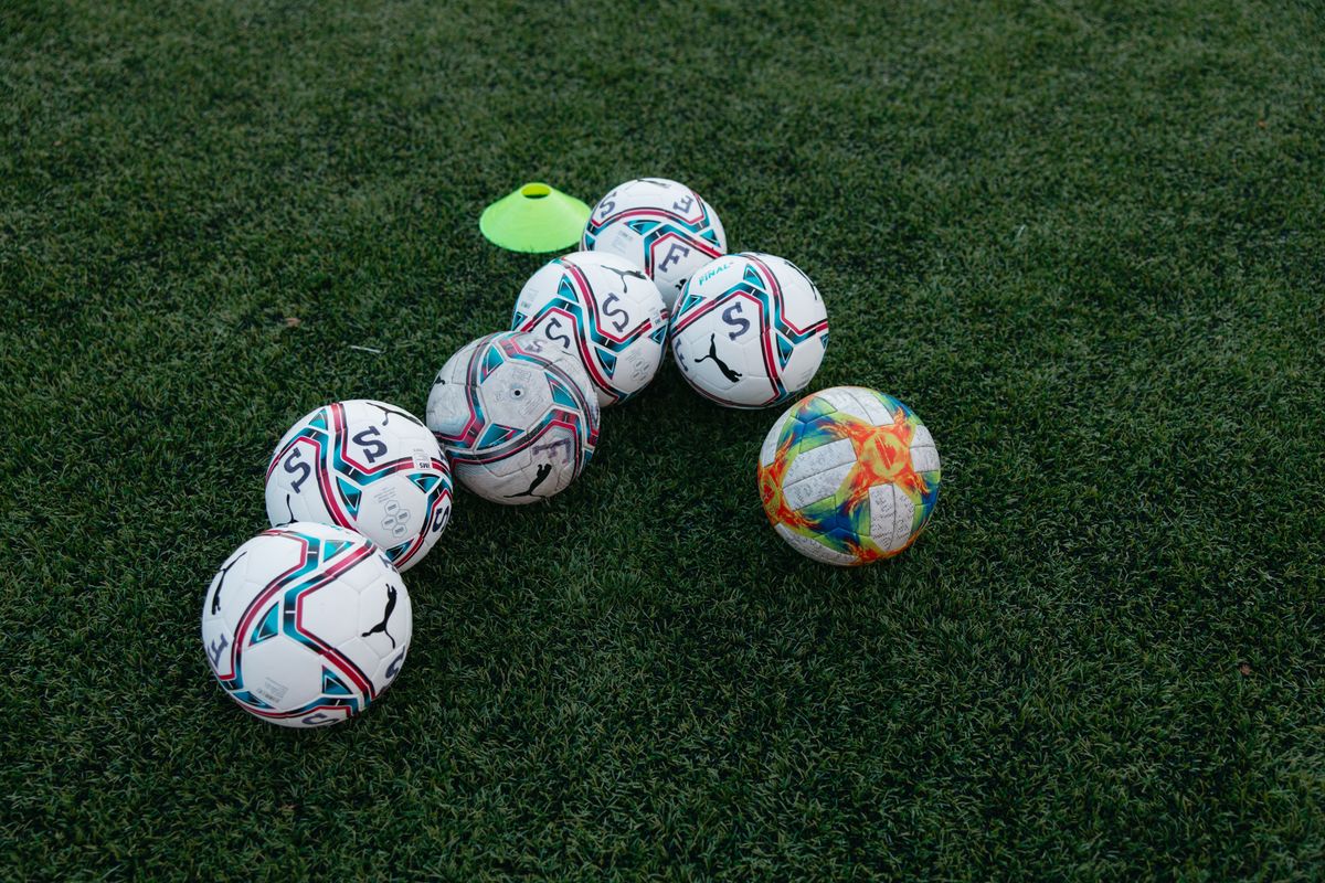 Yeşil çim üzerinde futbol topu ve iki takımın formaları yan yana