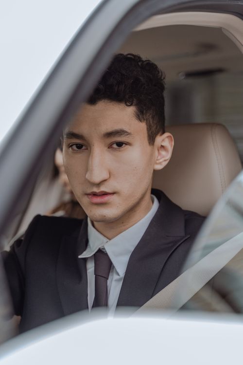 Free Portrait of an Asian man in a suit with an elegant demeanor, inside a car looking at the camera. Stock Photo