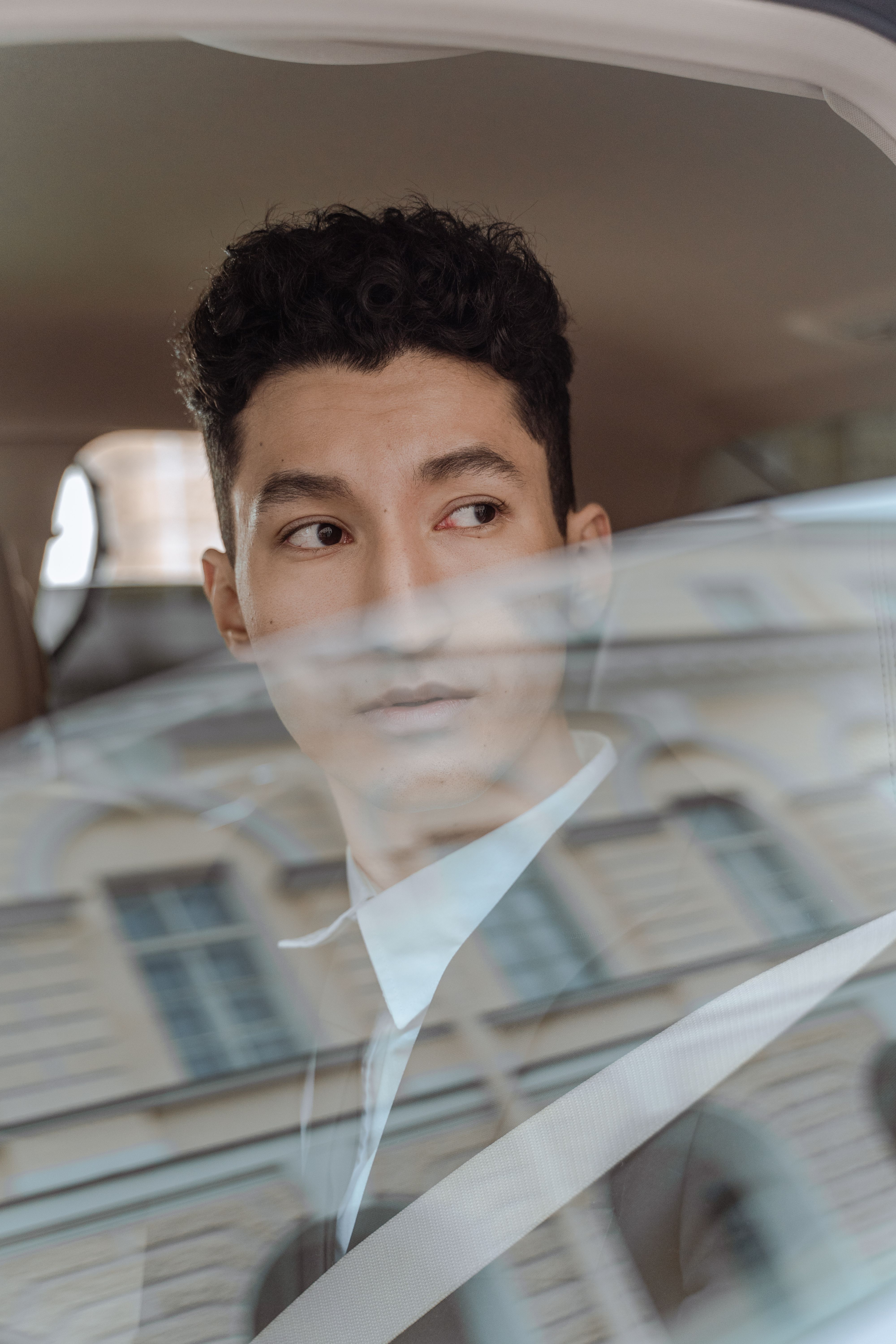 Portrait of a well-dressed man in a car looking thoughtfully through the window.