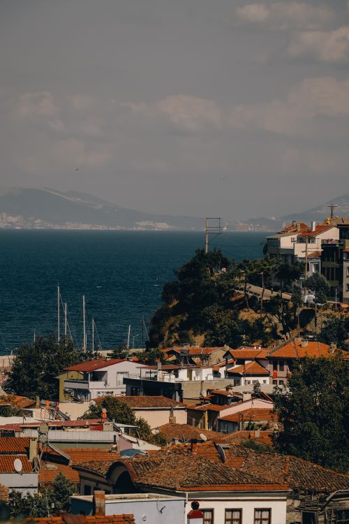 Free Aerial view of a coastal town with red rooftops and distant mountains across the sea. Stock Photo