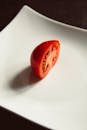 一片充满活力的红色番茄片摆在简约的白色陶瓷盘上