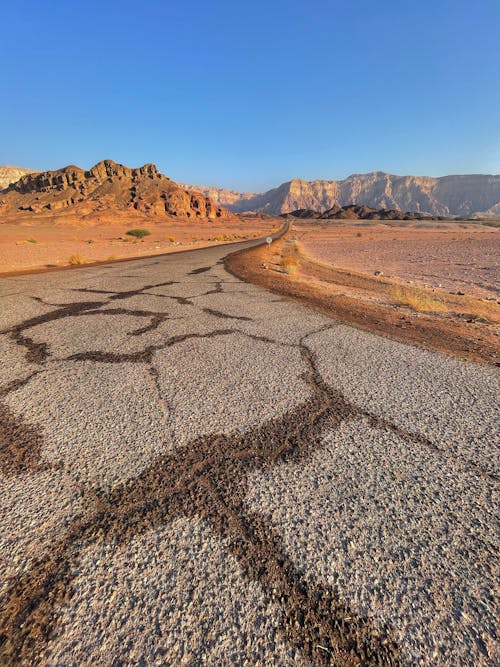 A Road with Cracks on a Desert Land Under Blue Sky
