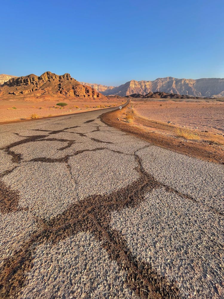 A Road With Cracks On A Desert Land Under Blue Sky