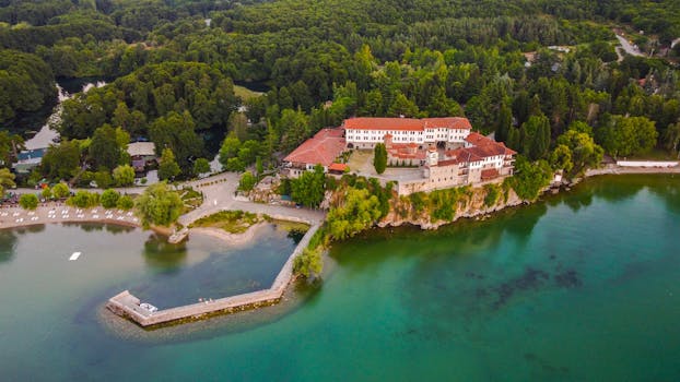 Scenic aerial shot of Saint Naum Monastery nestled by serene Lake Ohrid in Macedonia's lush landscape.
