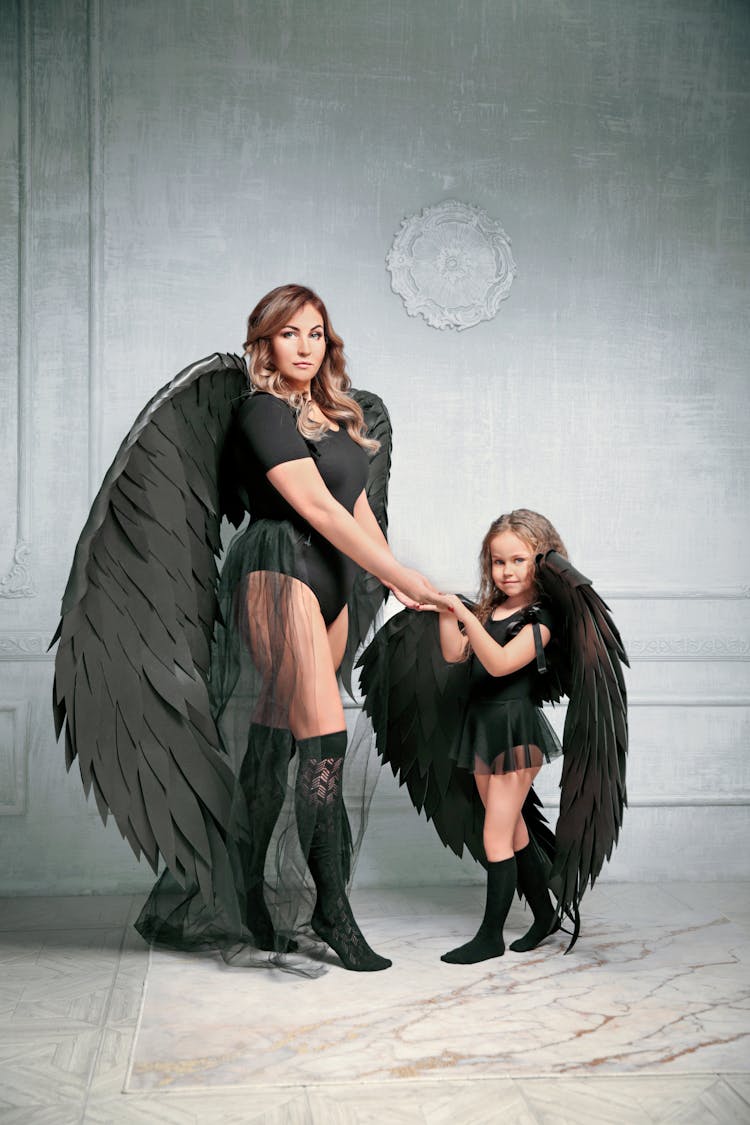 Mother And Daughter With Wings Posing In Studio