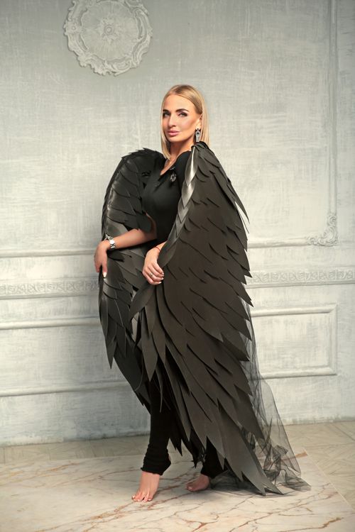 Free Woman poses gracefully with black angel wings in a sophisticated setting. Stock Photo