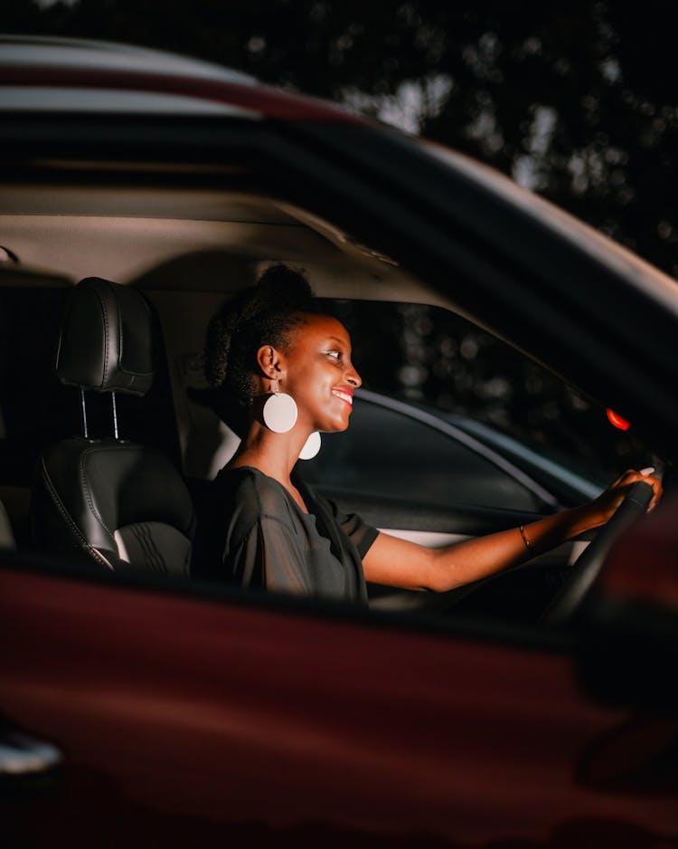 A Woman In Black Shirt Driving A Car During Night Time