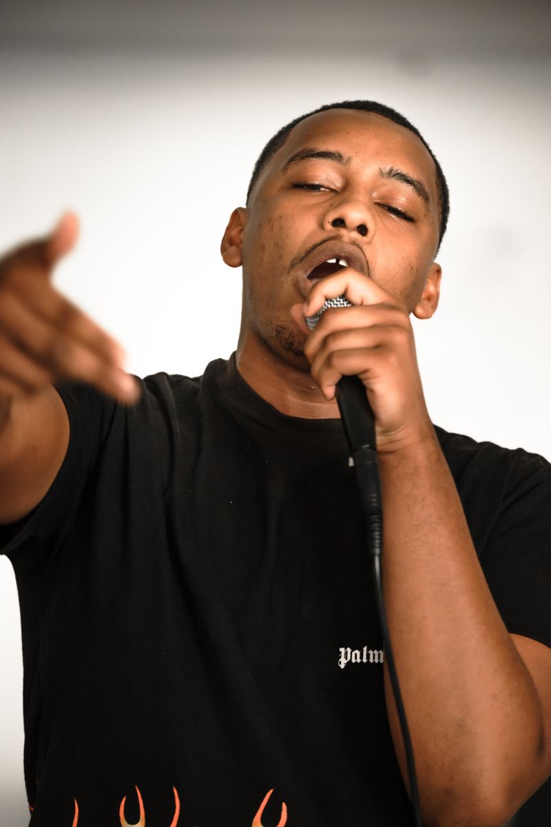 Passionate black male rapper in black T-shirt performing with microphone.
