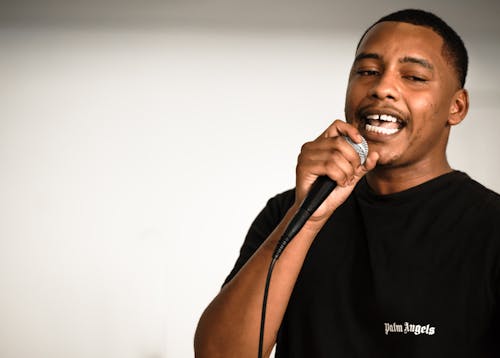 Man in Black Shirt Holding a Microphone on White Background