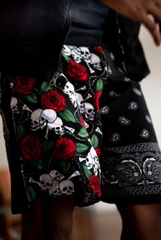 Stylish skull and rose patterned menswear shorts in a close-up view.