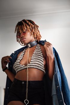 Fashionable african american woman in sunglasses modeling a modern outfit indoors.