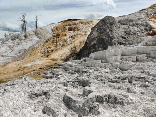Free A stunning view of an eroded rocky landscape with distinct layers and sparse trees under a cloudy sky. Stock Photo